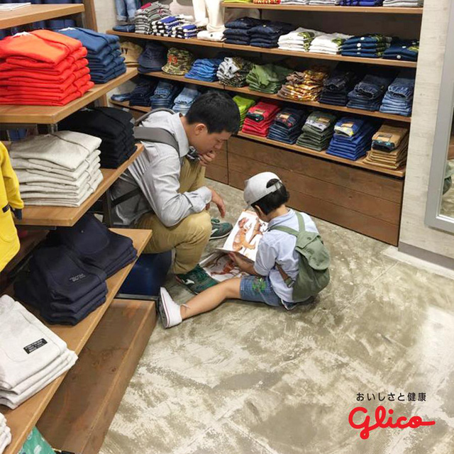 Hình ảnh một cậu bé đọc sách trong lúc chờ bố mẹ mua quần áo